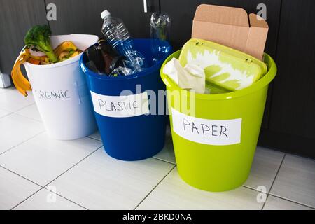 primo piano. Ordinare spazzatura a casa. Ci sono tre secchi per diversi tipi di rifiuti. Ordina rifiuti in cucina Foto Stock