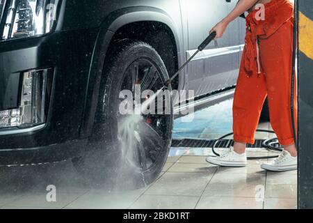 Auto lavaggio auto. Ruote di pulizia utilizzando acqua ad alta pressione. Foto Stock