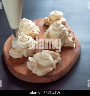 Il processo di creazione di Pavlova dessert, decorazione della meringa con crema Foto Stock