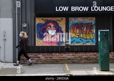 Portland, Stati Uniti. 3 maggio 2020. Una donna che indossa una maschera facciale passa accanto all'arte di strada a tema coronavirus a Portland, Ora., il 3 maggio 2020. (Foto di Alex Milan Tracy/Sipa USA) Credit: Sipa USA/Alamy Live News Foto Stock