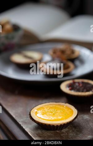 Piccole torte dai sapori diversi su un tavolo di legno Foto Stock