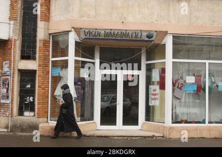 Persona che passa da un business privato al piano principale di un edificio di appartamenti a Focsani, Romania Foto Stock