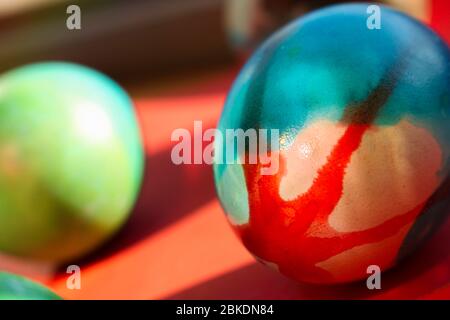 Uova colorate e vivaci per Pasqua in piedi su carta rossa e blu sfondo Foto Stock