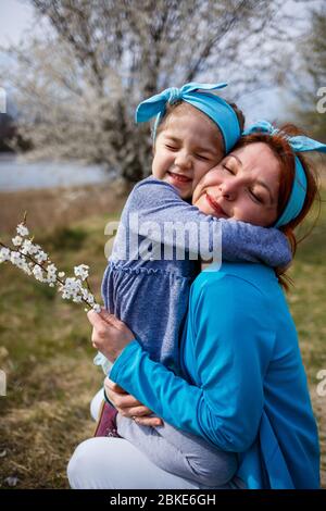 bambina bambino e madre donna cammina attraverso la foresta di primavera con alberi fioriti, risate e giocare, l'inizio della primavera, vacanza in famiglia, lov Foto Stock