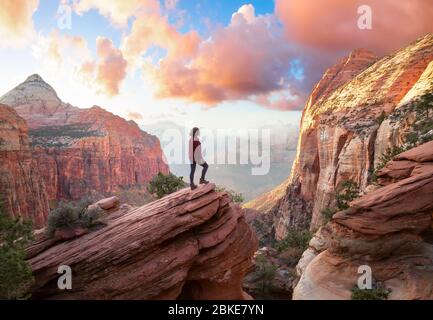 Adventurous Woman ai margini di una scogliera sta guardando una splendida vista del paesaggio nel Canyon Foto Stock