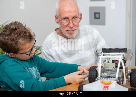 nonno e figlio ragazzino che riparano un modello di auto radiocomandata Foto Stock