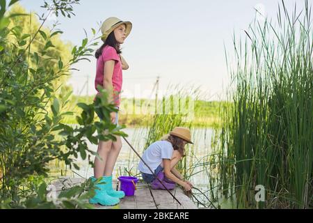 Bambini due ragazze insieme giocare con l'acqua sul lago sul molo di legno in canne Foto Stock