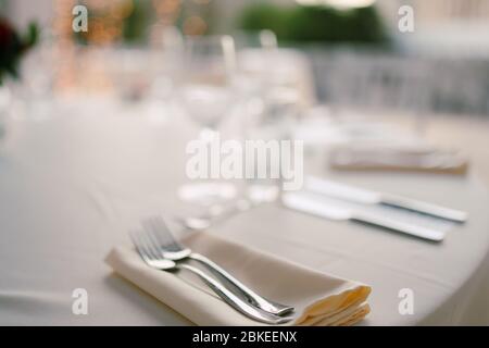 Primo piano di un tavolo da pranzo di nozze. Servire un tavolo da matrimonio - forchette giacciono su un tovagliolo. Foto Stock