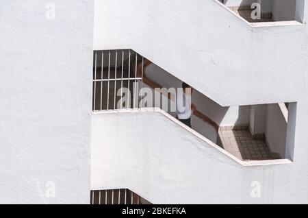 Parete bianca con balcone. L'uomo offuscato scende il volo di scalino. Stile urbano minimalista. Hong Kong Foto Stock