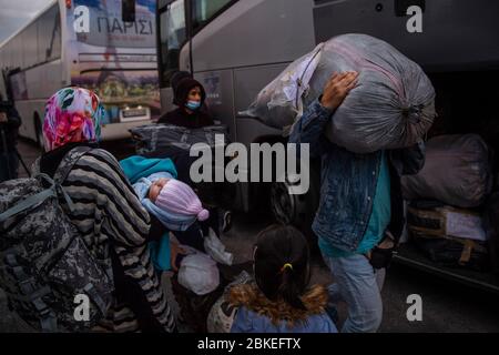 Athen, Grecia. 04 maggio 2020. I migranti provenienti dal campo di Moria, che sono arrivati in nave dall'isola di Lesbos, scavano a terra nel porto del Pireo vicino ad Atene e si fermano davanti agli autobus. Le autorità greche hanno trasferito circa 400 migranti, per lo più famiglie, sulla terraferma per alleviare la situazione nel sovraffollato campo di rifugiati di Moria sull'isola di Lesbos. Credit: Gdban/dpa/dpa/Alamy Live News Foto Stock