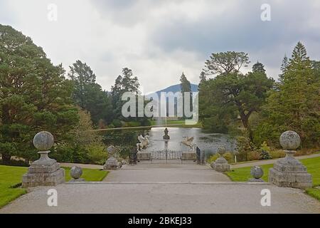 Lago Triton con fontana e alberi in giardini Powerscourt, con nebbiosa montagna di sugerloaf sullo sfondo. Enniskery, contea di Wicklow, Irlanda Foto Stock