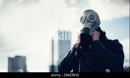 giovane uomo che indossa una maschera a gas su una strada della città Foto Stock