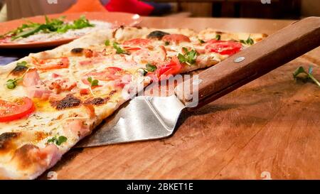 Spalmare con una fetta di deliziosa pizza italiana su un tavolo di legno in un ristorante al tavolo servito. Foto Stock