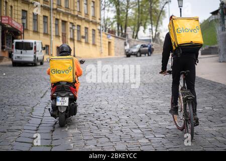 Due uomini di consegna Glovo garano con zaini Yellow Glovo in moto e su motobike. Concetto di servizio di consegna di cibo Glovo. Kiev, Ucraina, 24 del Foto Stock