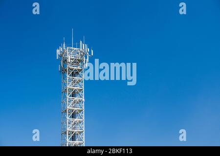 Torre per telecomunicazioni con antenne su cielo blu. Stazione base per sito cellulare 4G e 5G. Trasmettitore antenna di comunicazione wireless. Foto Stock