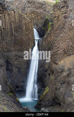 Lunga esposizione della splendida cascata di Littanesfoss, dove l'acqua cade tra le massicce geologie delle colonne basaltiche, l'Islanda. Foto Stock