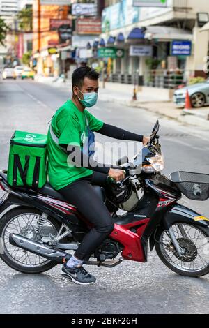 Prendi il conducente di consegna cibo con moto, maschera facciale e telefono cellulare durante Covid 19 epidemia, Bangkok, Thailandia Foto Stock