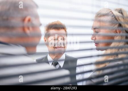 attraverso i ciechi. colleghi di affari che parlano in piedi nell'ufficio. Foto Stock