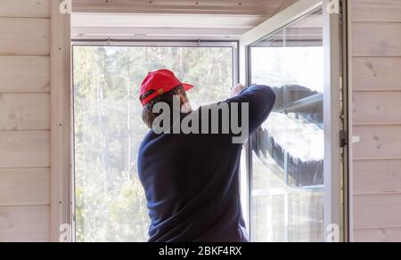 Lavoratore installare zanzariera o zanzariera filo schermo su finestra casa di legno. Foto Stock