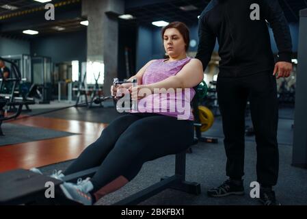 Donna in sovrappeso con allenatore in club sportivo Foto Stock