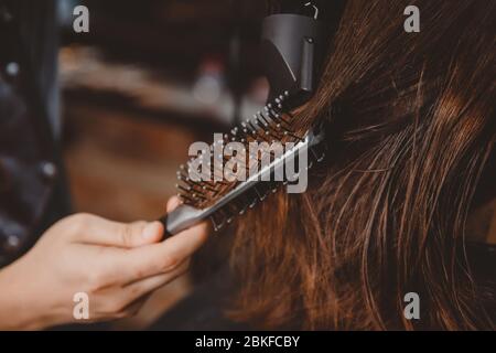 Barber rende l'acconciatura dei capelli all'uomo con asciugacapelli e pettine. Foto Stock