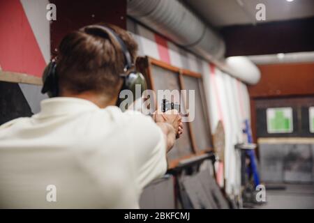 L'uomo dirige la pistola da arma da fuoco a portata di tiro o a portata di tiro. Foto Stock