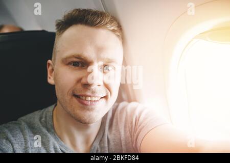 Felice uomo turistico fa foto selfie in aereo di cabina prima della partenza. Concetto di viaggio. Foto Stock