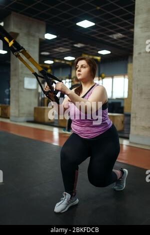 Donna in sovrappeso che fa esercizio di stretching in palestra Foto Stock