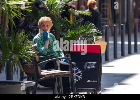 Barcellona, Spagna. 4rd Maggio, 2020. Donna anziana che indossa una maschera facciale e che siede su una panchina nel centro di Barcellona durante le ore in cui gli anziani sono autorizzati ad andare all'aperto Credit: Dino Geromella/Alamy Live News Foto Stock