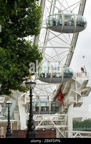 Un primo piano di una parte del London Eye o della ruota Millenium in una giornata nuvolosa a Londra con vecchi lampioni in primo piano. Foto Stock