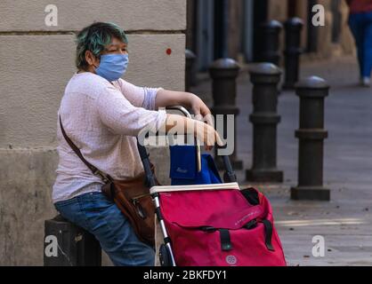 Barcellona, Spagna. 4rd Maggio, 2020. Donna anziana che indossa una maschera facciale e che siede su una panchina nel centro di Barcellona durante le ore in cui si trovano gli anziani Foto Stock