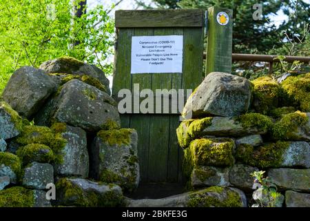 Richiesta di avviso non ufficiale sul cancello di legno con il cartello pubblico del sentiero (simbolo della freccia gialla a destra) durante il blocco del coronavirus - Yorkshire Inghilterra UK Foto Stock