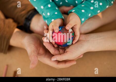 Colorful modeling palla di argilla in mano di bambino e genitori, orizzontale da sopra colpo Foto Stock