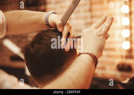 Il parrucchiere chiude le mani. Uomo taglio forbici capelli in stile loft salone di bellezza o barbiere negozio Foto Stock