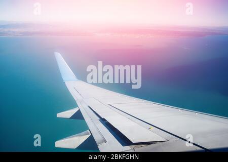 Concetto di viaggio. Ala di aereo sullo sfondo acqua turchese e spiaggia, evidenziare la luce del tramonto. Foto Stock