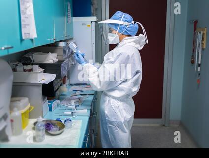 Covid-19 medico di prima linea impegnato nel trattamento dei pazienti. Foto Stock