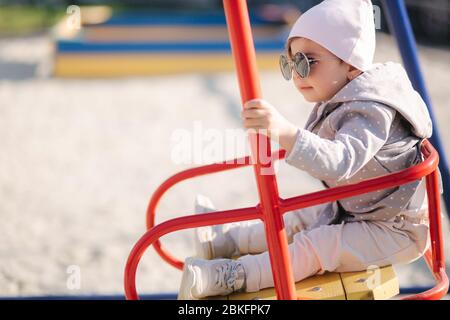 Adorabile bambina sul swing set nel parco giochi. Ragazza felice poco divertirsi. Una ragazza e hulf anno Foto Stock