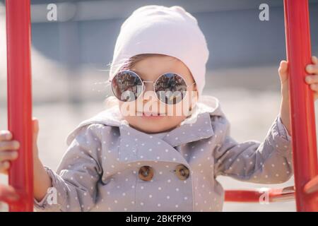 Adorabile bambina sul swing set nel parco giochi. Ragazza felice poco divertirsi. Una ragazza e hulf anno Foto Stock