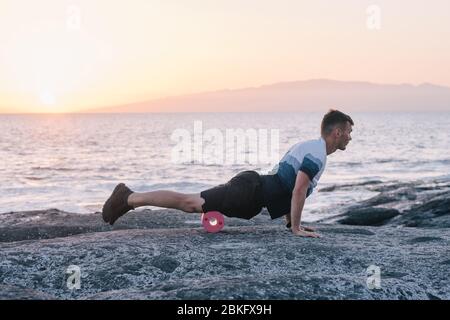Uomo che fa auto massaggio del corpo con un rotolo. Formazione fascia Foto Stock