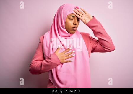 Giovane afro americano africano donna che indossa musulmano hijab su sfondo rosa isolato toccando fronte per malattia e febbre, influenza e freddo, virus malato Foto Stock