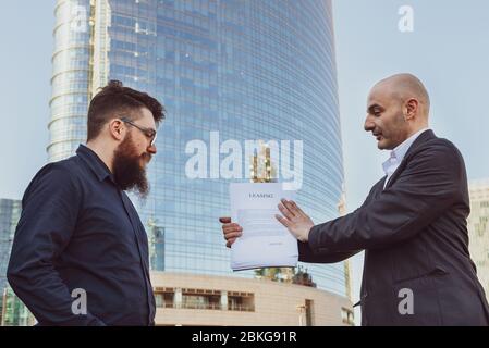Consulente finanziario spiega il contratto di locazione al cliente, avvocato amichevole fa una presentazione del contratto in presenza del futuro cliente Foto Stock