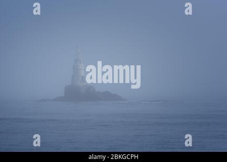 Faro lungo la costa rocciosa in mattinata Foggy Foto Stock