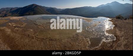 Piccola laguna in primo piano e vista panoramica delle montagne che circondano il sito geologico di Hierve el Agua. Foto Stock