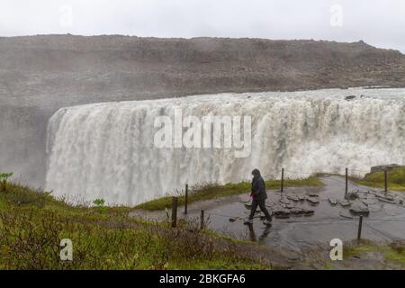 Un visitatore che passa davanti alla splendida cascata di Dettifoss nel Parco Nazionale di Vatnajökull, nel Nordest dell'Islanda. Foto Stock