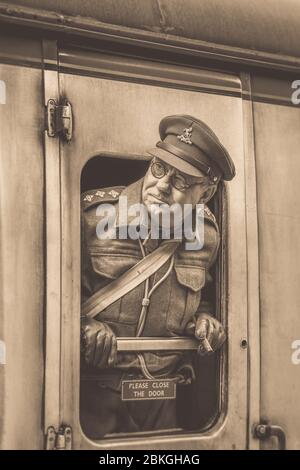 Seppia primo piano, uomo degli anni '40 come ufficiale della Guardia domestica della WW2 Captain Mainwaring (Arthur Lowe LookAlike) guardando fuori dalla finestra del treno d'epoca Severn Valley Railway. Foto Stock