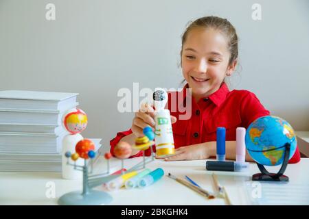 Primo piano Girl dopo la pittura modello astronauta legno con vernice acrilica colore sul tavolo da scrivania in casa bambini camera casa. Sfondo galassico a stella del cosmo in movimento Foto Stock