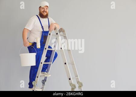 Pittura di pittore. Divertente pittore maschile con un pattinatore a rulli in piedi dipinge sullo sfondo. Foto Stock