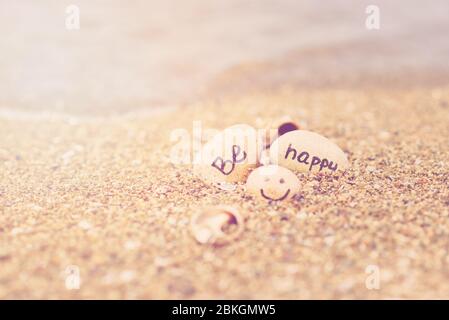 Bella luce del sole con sabbia pulita e le onde soffiano sulla spiaggia. Piccole rocce con iscrizione, vicino all'acqua. Foto Stock