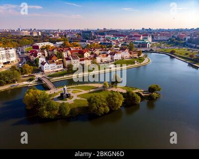 Isola verde di lacrime nel ponte del fiume centrale da cui conduce al vecchio quartiere storico con case tetti rossi in autunno Sunny giorno. Minsk, Repubblica Bela Foto Stock