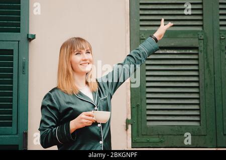 Bella giovane donna sorride e beve sensualmente mattina tazza di caffè in pajama. Prepararsi per lo yoga. Foto Stock